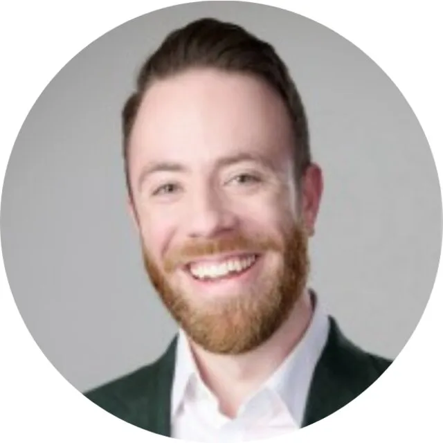 Callum Shaw smiling, in a jacket and open-necked shirt