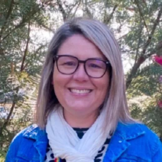 Kylie Loy smiling in a denim jacket and scarf, standing in the garden