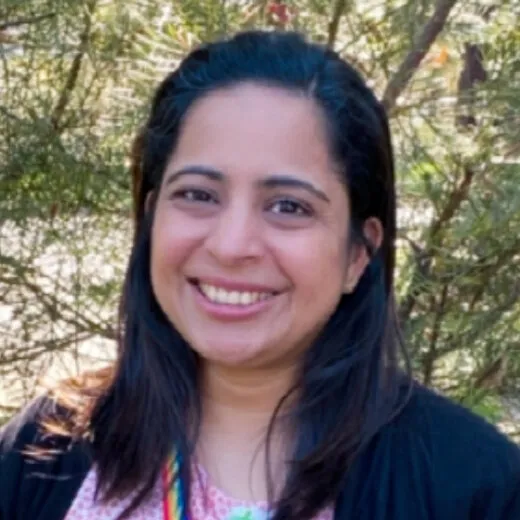 Tassia Moniz smiling in the garden, wearing a lanyard