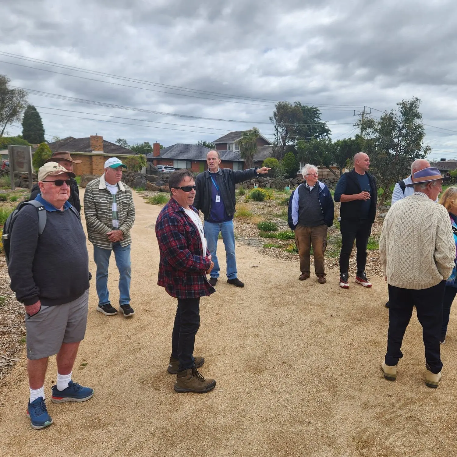 Men from the group standing and talking together on a gravel path at a heritage farm site